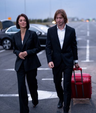 Business Couple Walking With A Suitcase On Parking Lot